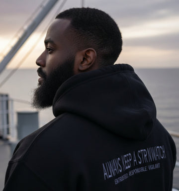 Man wearing a black hoodie with text on the back, standing outdoors.
